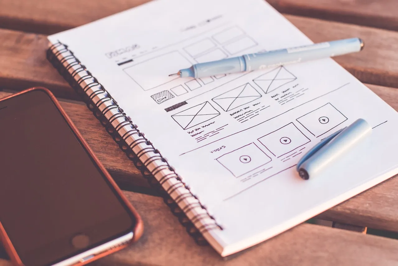 table with notebook where a wireframe of a website is drawn